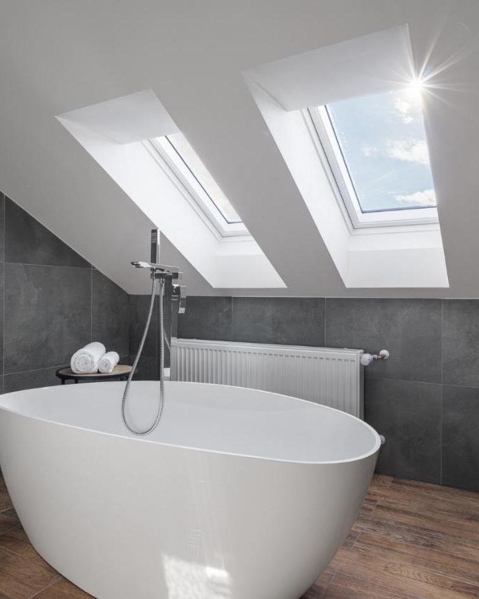 Freestanding bath beneath a skylight in a slate-tiled bathroom